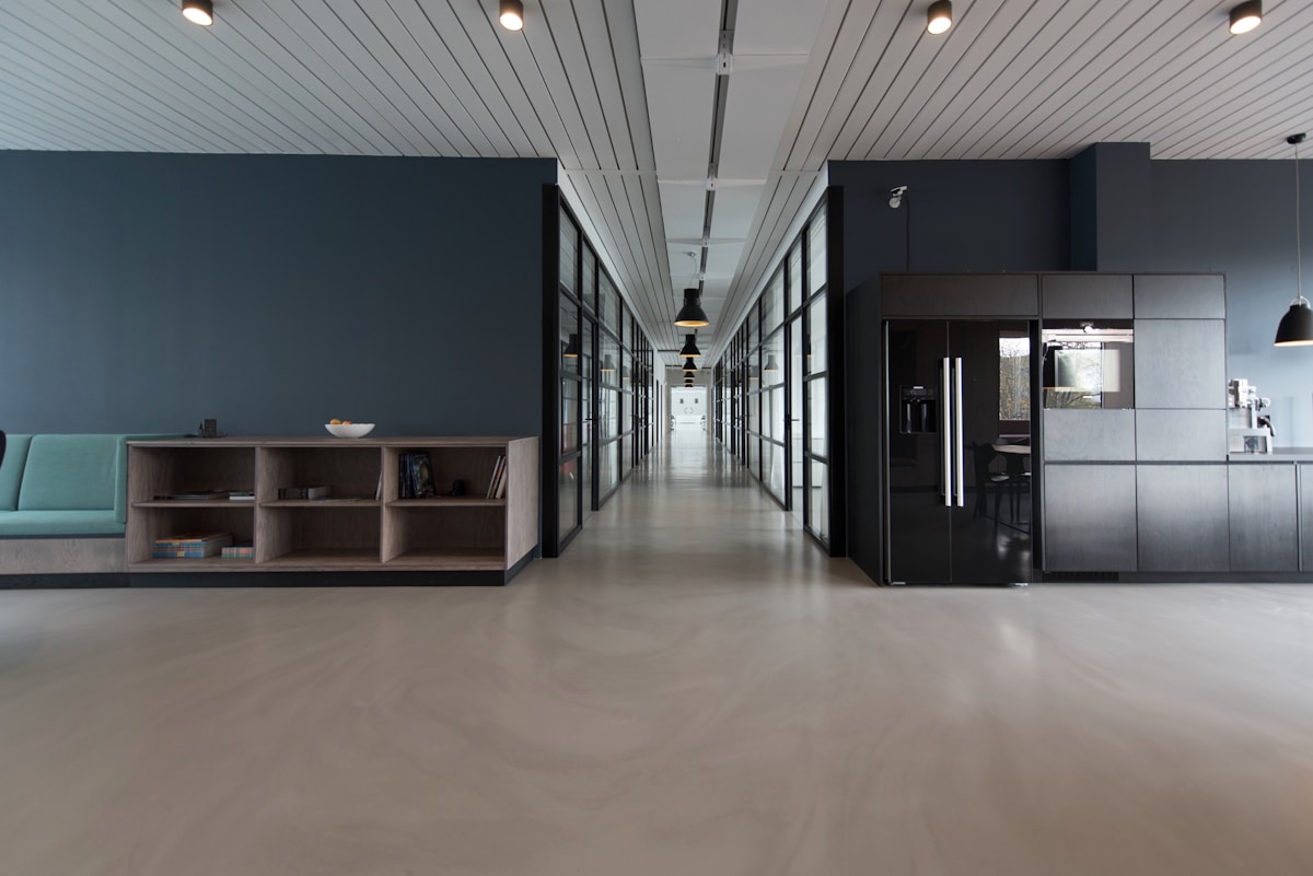 An empty office corridor with dark walls and low light.